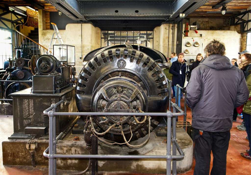 Visitors view a historic industrial machine in a museum.